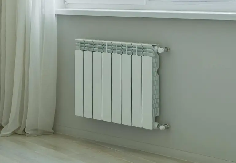 Weiße Heizung unter einem Fenster montiert